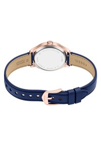 Montre femme Fossil avec un boîtier en acier inoxydable rose doré, un bracelet en cuir bleu, de forme ronde, et une surface lisse et texturée.