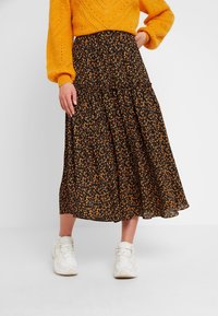 Black floral midi skirt with orange and yellow patterns, flared silhouette, lightweight fabric, paired with white athletic sneakers.