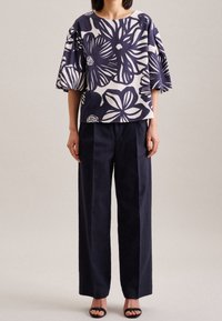 Top a stampa floreale in navy e crema, con maniche ampie e una vestibilità rilassata, abbinato a pantaloni scuri in navy a vita alta.