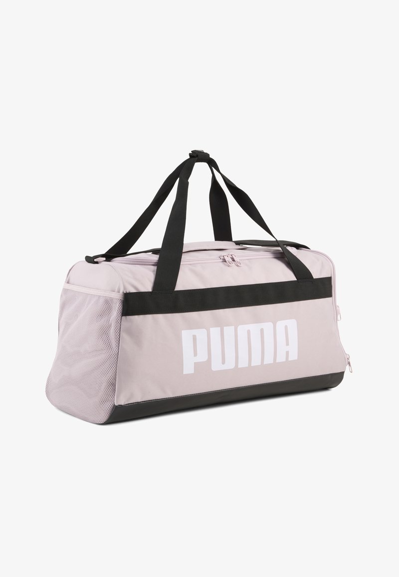 Ανοιχτό ροζ τσάντα Puma duffel με μαύρες λαβές, μαύρο κάτω περίγραμμα, πλευρική τσέπη από δίχτυ και μεγάλο λευκό λογότυπο Puma στο μπροστινό πάνελ.
