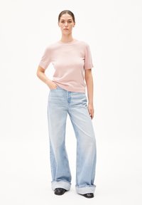 Light pink knit short-sleeve top paired with high-waisted, wide-leg light blue denim jeans. Black ankle boots complete the outfit.