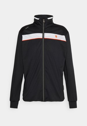 Zwarte jas met een volledige ritssluiting en een hoge kraag, witte horizontale streep over de borst, daaronder een dunne rode lijn en een klein oranje embleem aan de linkerkant.