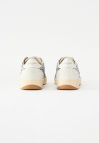 Sneaker bianche con accenti di glitter argento ai lati, retro in suede e suole in gomma leggera color tan. Branding Blauer vicino al tallone.