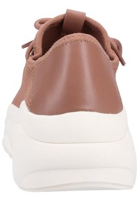 Zapatilla marrón con parte trasera de cuero suave, parte superior de tela y una suela blanca gruesa. Cuenta con un diseño de cordones y una lengüeta en el talón.