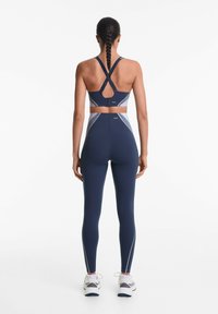 Marineblauwe sportbeha met kruisbanden en een sleufontwerp, gecombineerd met bijpassende hoge taille legging met witte zijstrepen.