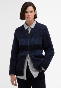 Marine gebreide cardigan met ritssluiting aan de voorkant, voorzien van horizontale gestreepte patronen in verschillende schakeringen van blauw, textuurstof en geribbelde manchetten.