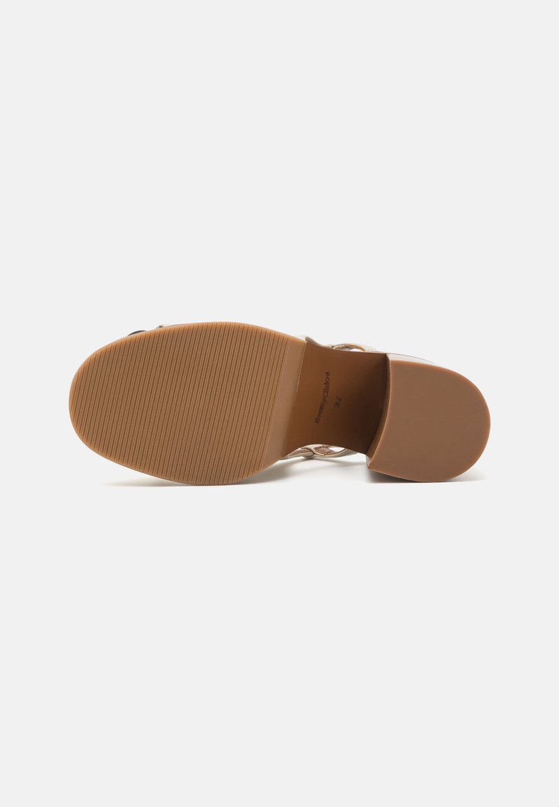 Braune Gummisohle mit texturierten Oberflächen. Das Obermaterial verfügt über ein filigranes Design mit offenen Bereichen und einem niedrigen Absatz.