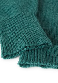 Tyrkysový pletený svetr s žebrovanou texturou a ohrnutými manžetami, vyrobený z měkké a пухové příze. Viditelné stehy a tloušťka jsou výrazné.