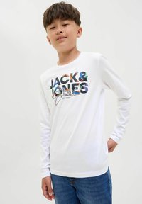 T-shirt bianco a maniche lunghe con una grafica colorata "JACK & JONES" sul davanti, abbinato a jeans blu e con una vestibilità rilassata.