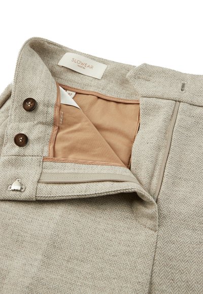 Tijdloos houndstooth-patroon in tan kleurige broek met een rits, twee knopen en een beige voering. Voorzien van een zilverkleurig accentelement op de tailleband.