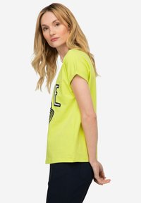 Camiseta de manga corta amarilla neón con un estampado gráfico en negro. Fabricada con un tejido suave, tiene un corte relajado y un cuello redondo.
