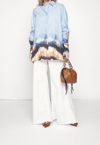 Light blue button-up shirt with a gradient print, white wide-leg pants, and a brown handbag with a chain handle and drawstring closure.