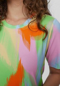 Tricou cu mânecă scurtă, de tip crew-neck, având un model abstract vibrant, multicolor în nuanțe de verde, portocalie, roz și albastru. Textură de țesătură moale.