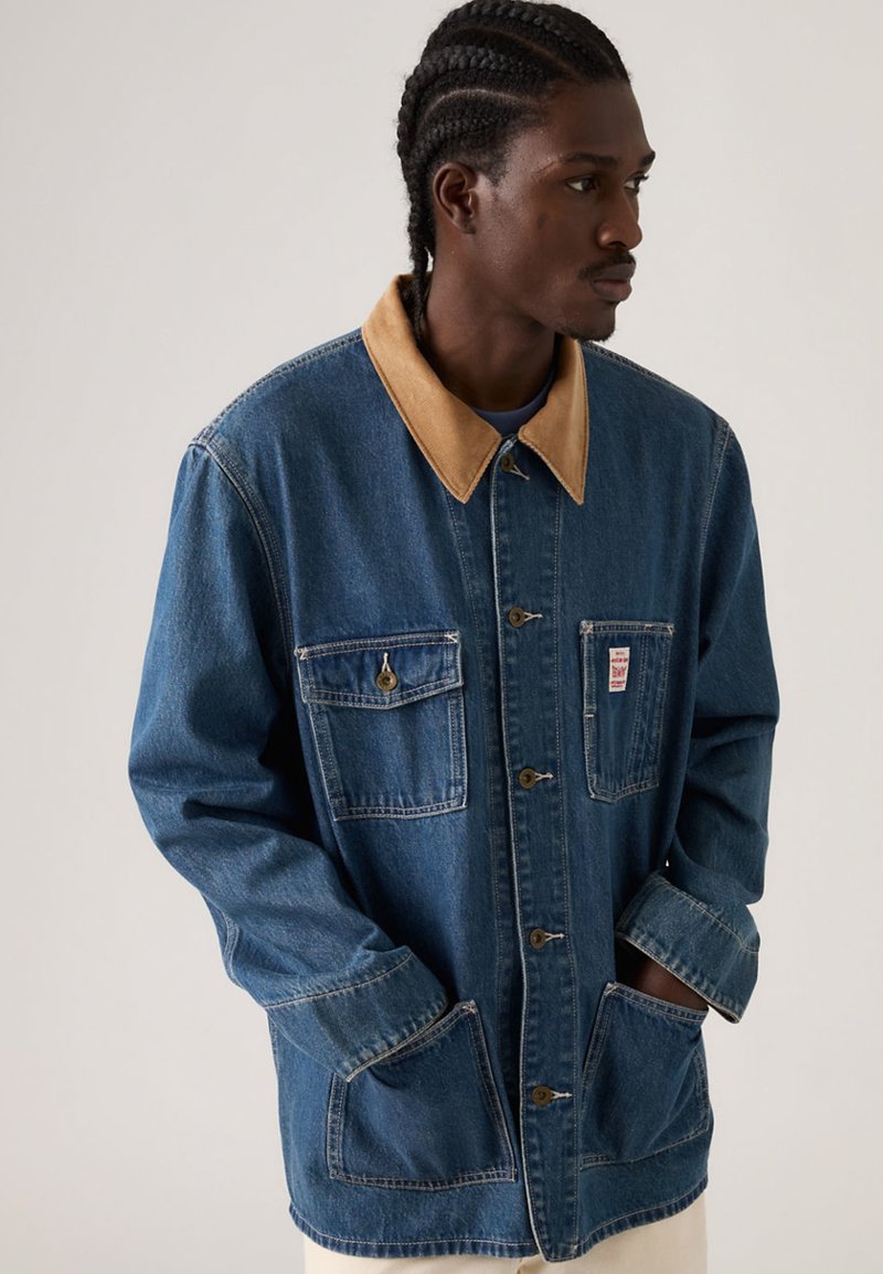 Τζιν μπουφάν με ταμπά γιακά, κουμπιά μπροστά, δύο τσέπες στο στήθος και ρυθμιζόμενες μανσέτες. Διαθέτει άνετη εφαρμογή και ορατές ραφές.