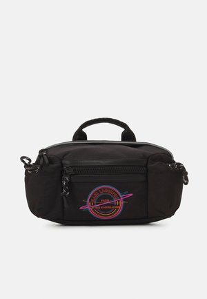 Schwarze Nylon-Tasche mit einem Oberhandgriff, ausgestattet mit einer vorderen Reißverschlusstasche und einem bunten runden Logo. Glatte Textur und abgerundete Kanten.