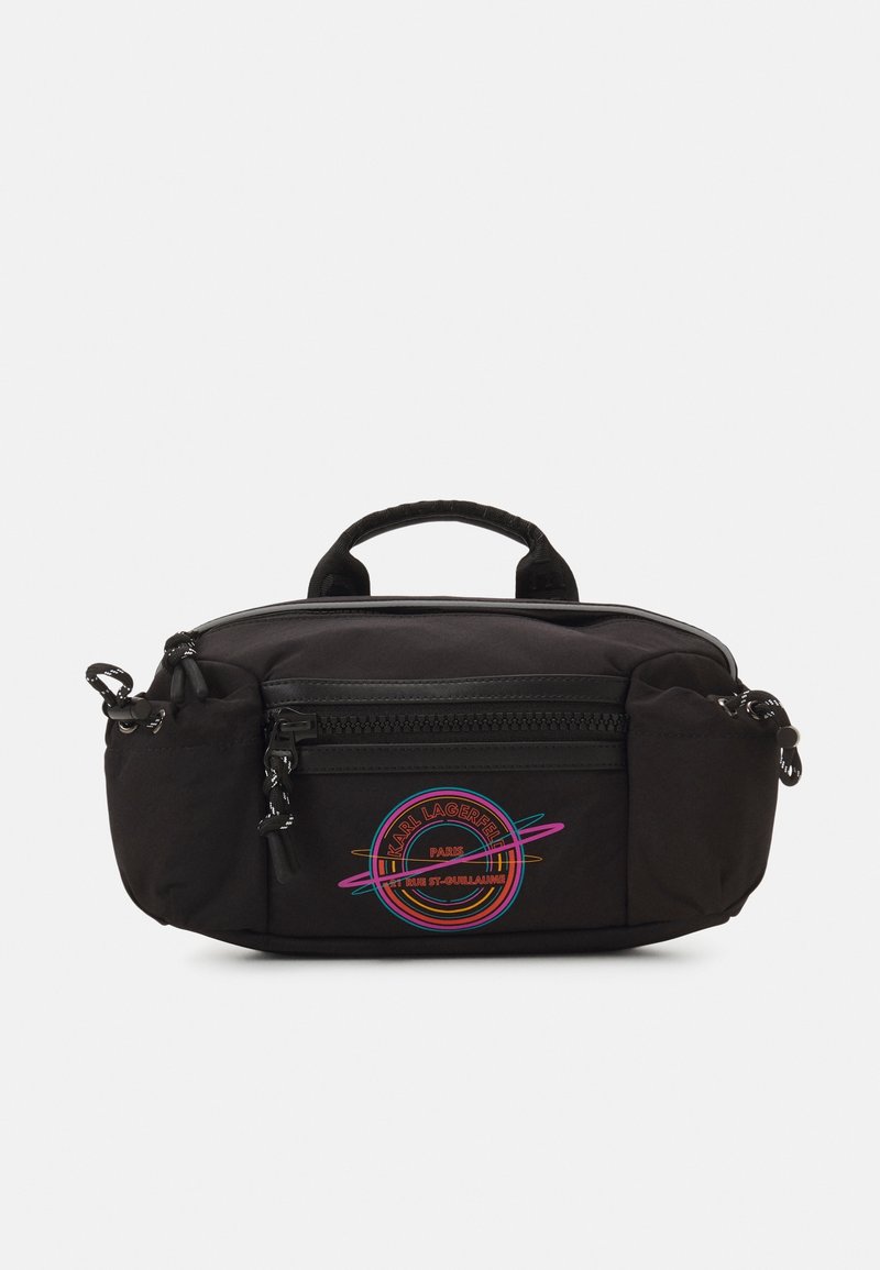 Borsa nera in nylon con manico superiore, dotata di una tasca frontale con zip e un logo circolare colorato. Texture liscia e bordi arrotondati.