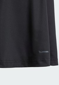 Mustmust mustere, millel sile peale pehmus, mis sisaldab hingavat disaini. Vooderdav "CLIMACOOL" logo hemmi lähedal.