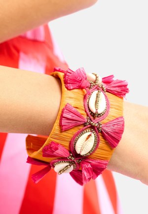 Bracelet tressé coloré en orange avec des pampilles roses, des accents de coquillages et des détails en perles métalliques. Présente un large design manchette.