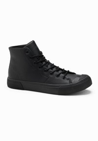 Černé vysoké tenisky vyrobené z hladké kůže, s kulatou špičkou, šněrováním vpředu, polstrovaným límcem a gumovou podrážkou. Minimalistický design bez ozdob.