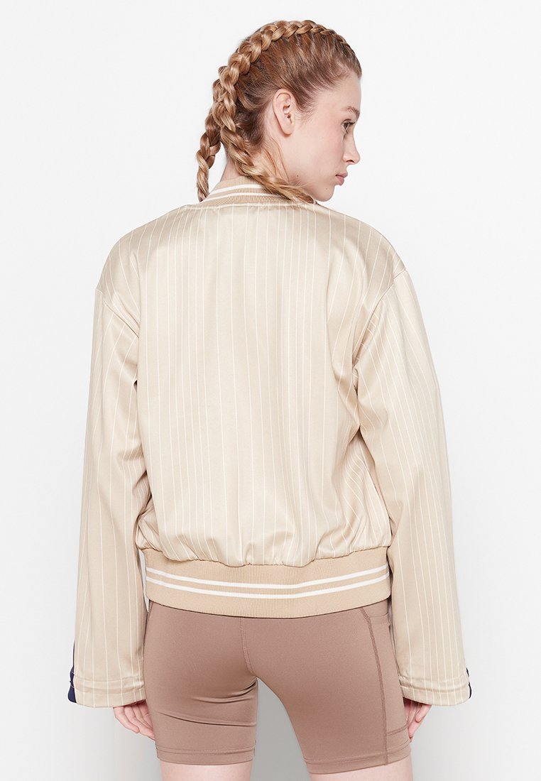 Chaqueta bomber de satén beige con rayas verticales, bajo de canalé y corte holgado. Presenta mangas anchas y una textura suave.