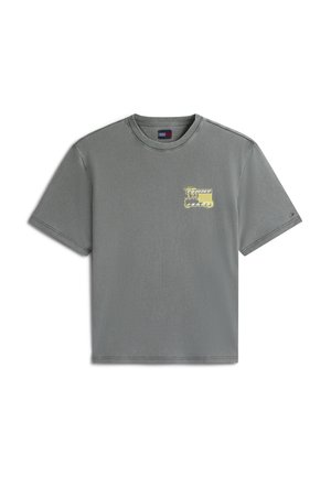 T-shirt gris à manches courtes et col rond avec un petit motif jaune et noir sur le côté gauche de la poitrine et un petit détail de drapeau sur la manche gauche.