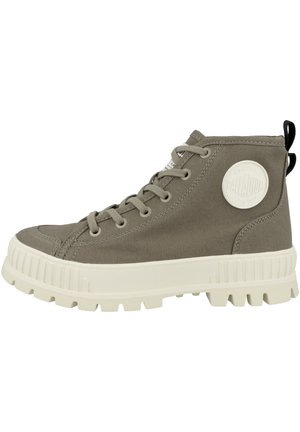 Zapatillas altas de lona en color verde oliva con suela de goma blanca. Incluyen características como puntera redonda, diseño de cordones y parche con el logo en el lateral.