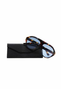 Occhiali da sole tartarugati con lenti blu appoggiati su una custodia nera texture. La montatura è angolare con schemi di colore distintivi.