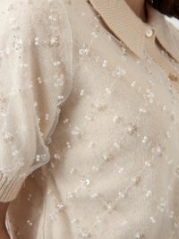 Μπεζ πλεκτό πουλόβερ με γιακά, με διάφανο ύφασμα καλυμμένο με λουλουδένια μοτίβα, χάντρες και παγιέτες σε όλο το κομμάτι.