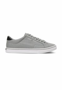 Baskets basses grises avec semelle blanche, lacets à l'avant, languette de talon noire et petit logo Tommy Hilfiger sur le côté.