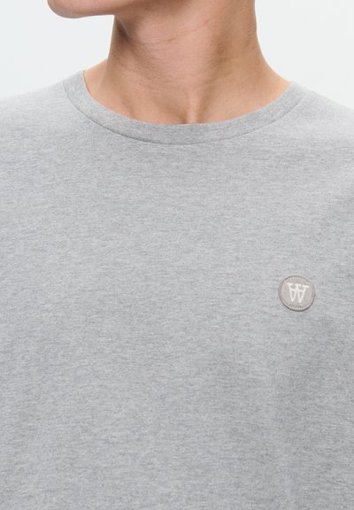 Gray cotton t-shirt with a round neckline, featuring a small round logo patch in a light gray color on the chest. Smooth texture.