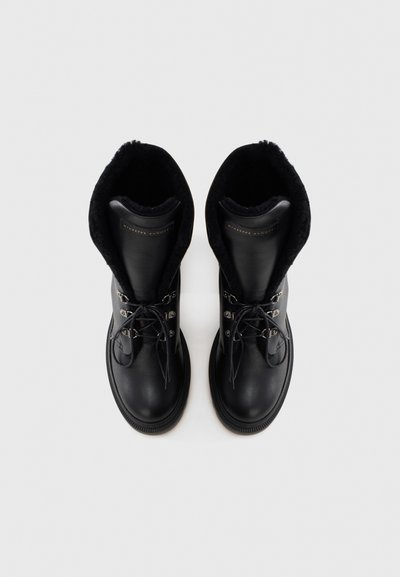 Czarne skórzane buty za kostkę z miękkim, czarnym futrzanym wyściółką, sznurowane z przodu, ozdobione srebrnymi elementami. Zaokrąglony nosek i gruba gumowa podeszwa.