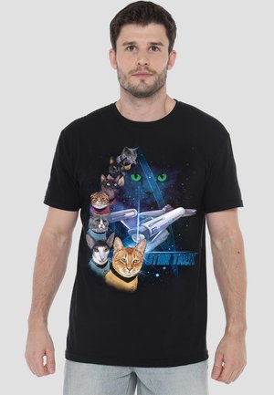 Black t-shirt featuring a graphic design of cats and a starship, with vibrant colors and space theme. "STAR TREK" text in blue below the graphic.