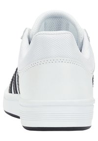 White sneaker with a smooth leather heel and textured mesh upper. Features vertical black stripes and a rubber sole with horizontal grooves.