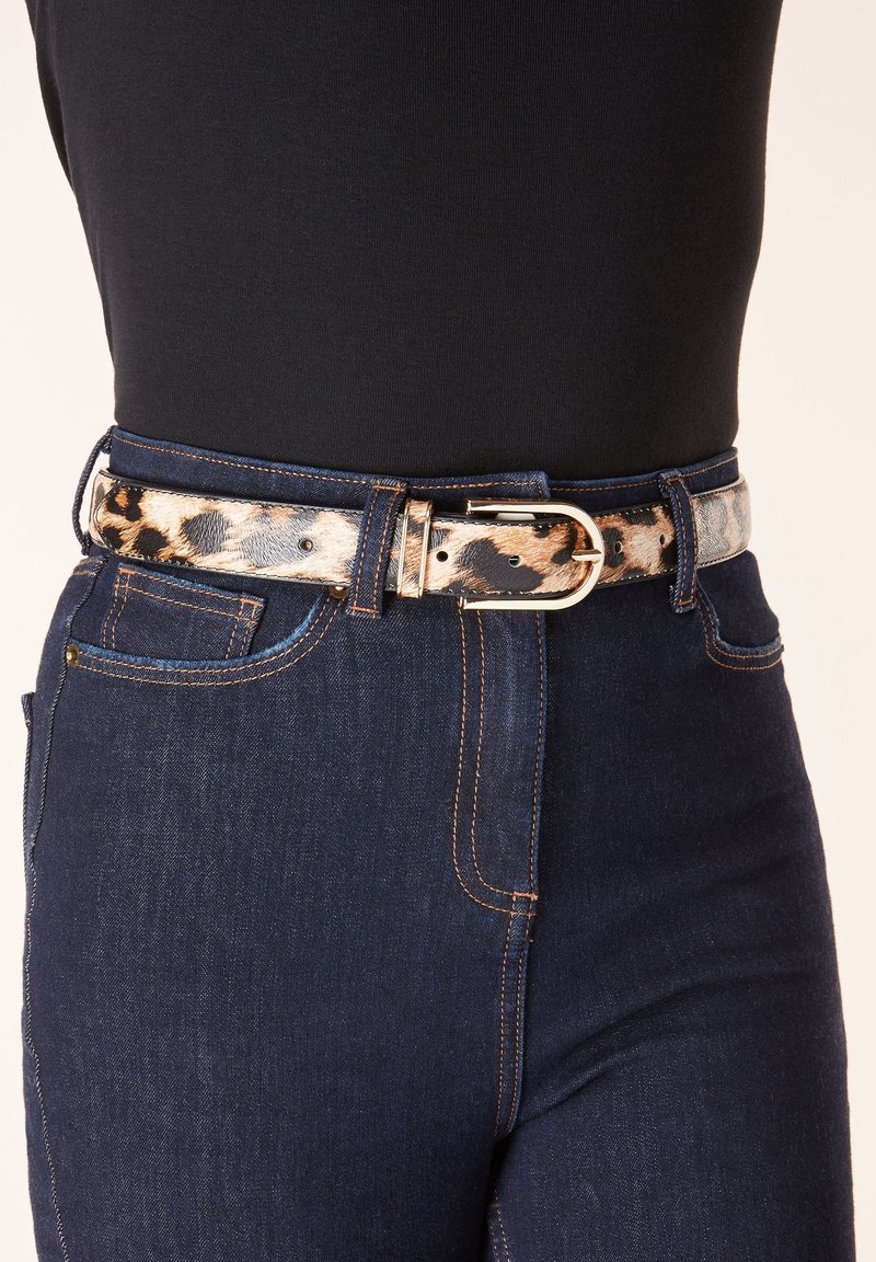Ceinture à imprimé léopard avec boucle dorée portée avec un jean taille haute bleu foncé et un top noir rentré.