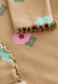 Tessuto marrone rigato con motivi floreali colorati in rosa, verde e turchese. Include bordi arricciati per un maggiore effetto di tessitura.