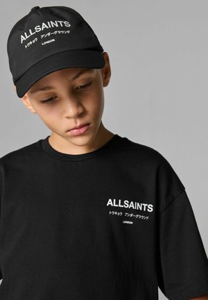 Musta puuvillainen t-paita lyhyillä hihoilla; sisältää valkoista painettua tekstiä, mukaan lukien "ALLSAINTS" ja lisämerkkejä. Yhdistetty yhteensopivan mustan lippiksen kanssa.