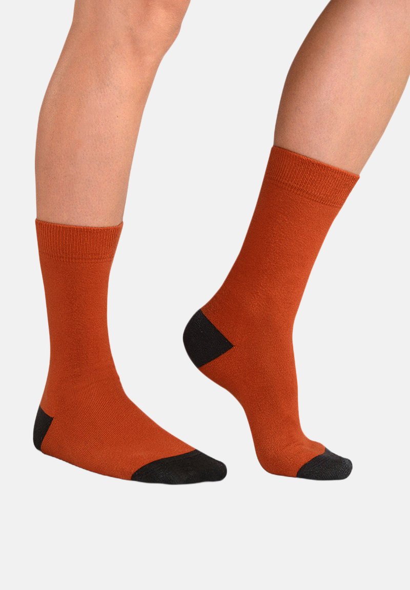 Orange bomuldsstrømper med ribbet manchet, med sorte detaljer ved hælen og tåen. Glat tekstur, mellemhøjde til læggen og enkelt design.