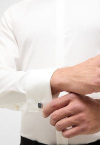 Witte overhemd met lange mouwen, voorzien van een zilveren manchetknopen met een getextureerde zwarte accent. Glad materiaal en op maat gemaakt fit.