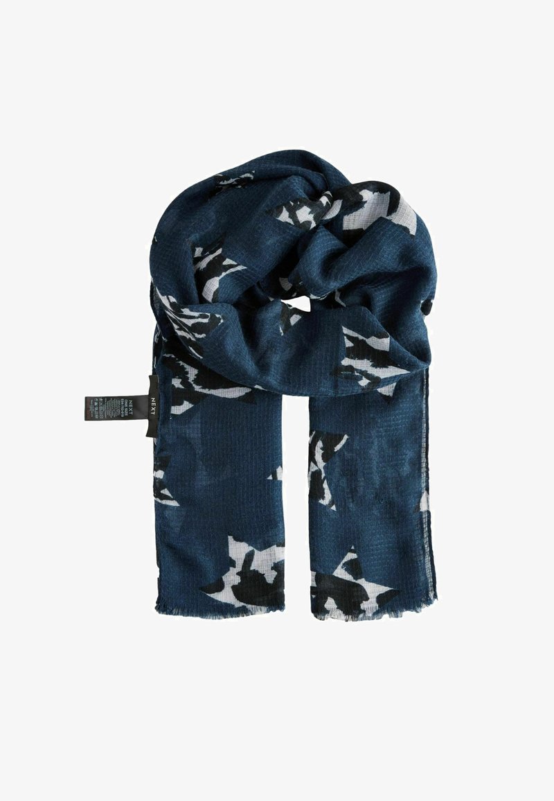 Écharpe bleue à motif en tissu texturé, ornée de formes abstraites noires et blanches, avec des bords effilochés et une étiquette d'entretien attachée.