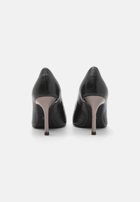 Scarpe nere in pelle con tacco alto, punta affusolata e sottile tacco a stiletto argentato, caratterizzate da una texture liscia e un design minimalista.