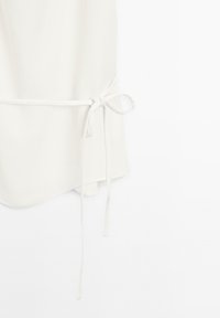 Witte top gemaakt van zachte stof, met een strik in de taille, een afgeronde zoom en een gladde textuur. Ontworpen voor een ontspannen pasvorm.