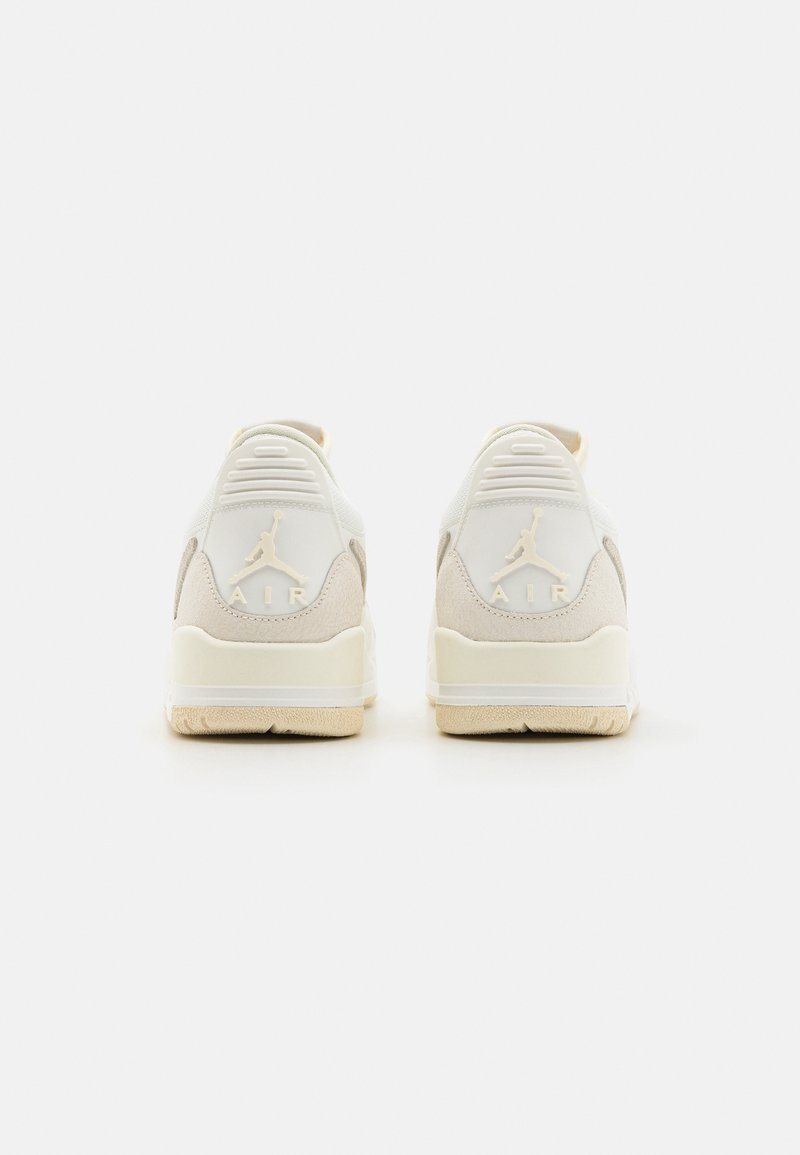 Zapatillas blancas y beige con parte superior de ante y cuero. Logo en el talón, suela con patrón. Diseño minimalista, estilo bajo.