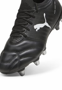 Czarny korki piłkarskie z teksturowanym syntetycznym wierzchem, elegancki design, sznurowane zapięcie, białe logo Pumy i metalowe wkręty na podeszwie.