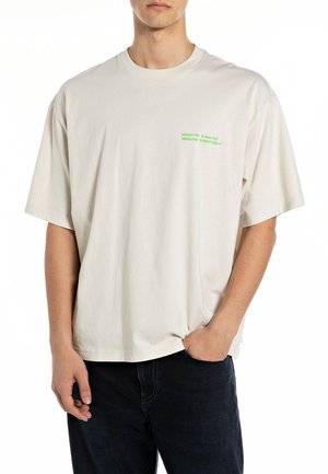 Light beige t-shirt with a relaxed fit, short sleeves, and a round neckline. Features green text on the chest: "work hard, save harder."