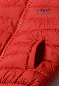Giacca a vento rossa con design trapuntato, zip frontale e tasca sinistra. Il logo del marchio "MN97 NEVER STOP 97" è ricamato in blu.