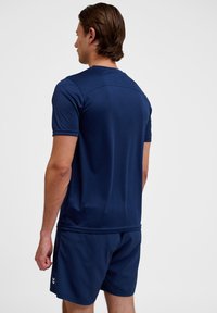 Marineblauw sport T-shirt met korte mouwen, een gladde textuur en een fitted ontwerp, gecombineerd met bijpassende shorts met zijaccenten.