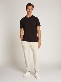 Black short-sleeve t-shirt, light gray sweatpants with elastic cuffs, and white sneakers. Simple design, minimal detailing, and soft texture.