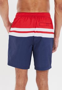 Pantaloni da nuoto da uomo con vita rossa, strisce bianche e rosse e parte inferiore blu navy. Realizzati in tessuto leggero e a asciugatura rapida.