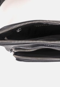 Borsa in pelle nera con numerosi scomparti con zip, texture liscia, hardware della zip in argento e un design semplice e funzionale.