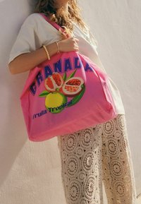 Sac fourre-tout rose avec un design graphique de grenade et citron, accompagné du texte « Granada Fruta Tropical ». Le matériau semble être une toile.